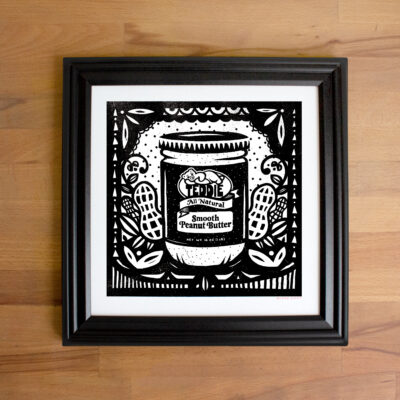 A photo of a black and white peanut butter illustration in a black frame.